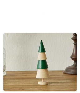 Detail of wooden mini Christmas tree with layered green and natural wood tiers on table