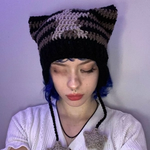 Detail of hand-knitted cat ear hat with striped pattern and star-shaped crochet pendants