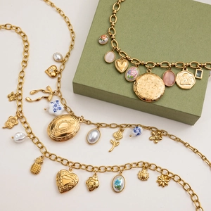 Retro gouden gelaagde ketting met vintage bedeltjes en parels op lichte achtergrond