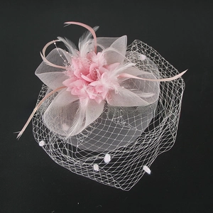 Detail view of pink floral fascinator with delicate feathers and mesh for weddings