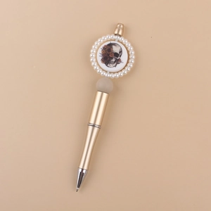 Close-up of champagne gold beaded pen with a pearl-ringed floral skull badge detail