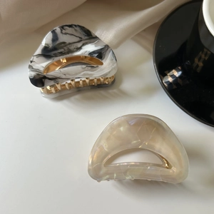 Detailed view of marble and pearlescent acetate hair claws on a soft silk background