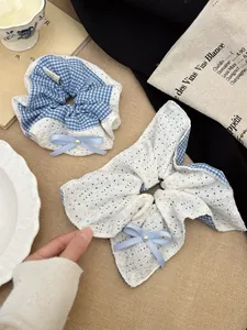 Detailed shot of blue plaid and lace bow scrunchie with pearl on an elegant table