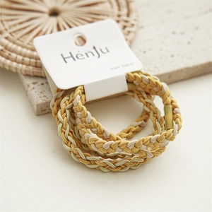 Detailed macro view of three braided yellow hair ties on a branded display card