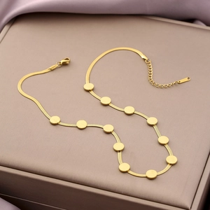 Close-up of gold snake chain necklace with flat circular discs and secure lobster clasp