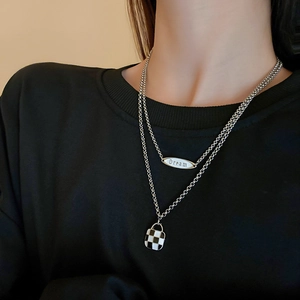 Detail of double-layer necklace featuring a black-white checkerboard and Dream pendant
