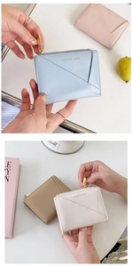 Detail of compact zip wallets with V-shaped stitching in pastel blue, pink, and beige