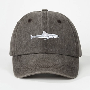 Detailed close-up of white shark embroidery on charcoal washed cotton baseball cap