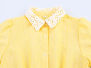 Close-up of sweet yellow shirt dress featuring white lace collar and button details
