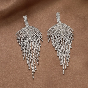 Sparkling silver feather tassel earrings with rhinestones on a brown silk background