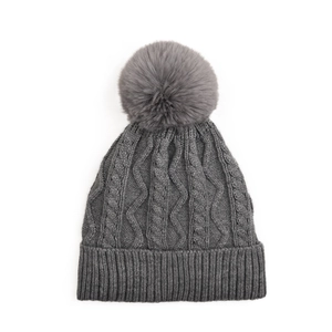 Close-up of thick cable knit winter hat in dark grey with fluffy pom-pom detail