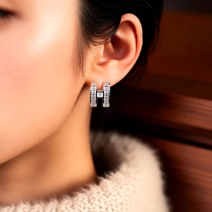 Macro shot of a silver H-letter ear cuff with sparkling zircon inlay on model's ear