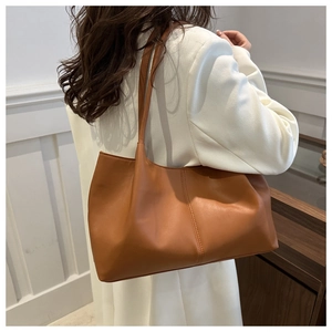 Detailed view of brown leather tote bag with decorative stitching on professional suit