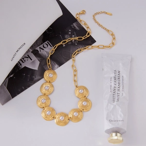 Macro shot of gold-plated pearl necklace with grooved round pendants and heavy link chain