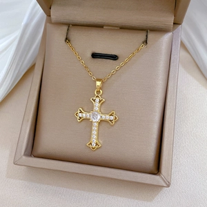 Macro detail of gold cross necklace with zircon crystals in a beige jewelry gift box