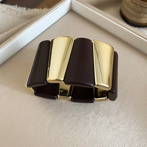 Detailed macro view of retro brown acrylic and gold metal geometric block stretch bracelet