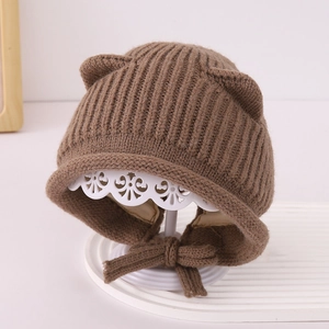 Dettaglio trama a maglia e orecchie su cappello marrone neonato con lacci