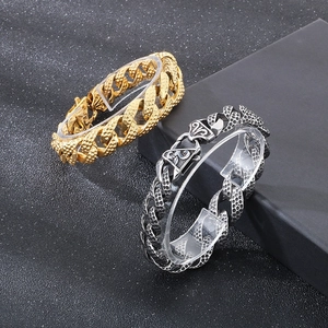 Close-up of gold and silver Cuban bracelets with hammered texture on black display