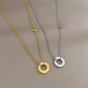 Macro detail of gold and silver layered necklaces with circular LOVE engraved pendants