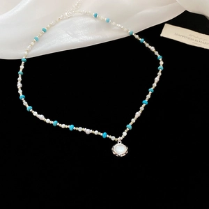 Dettaglio della collana di perle e turchese con pendente a conchiglia su tessuto di seta