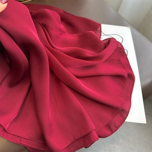 Detail of red satin scarf fabric showing soft texture and glossy smooth drapes