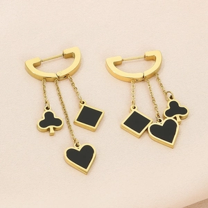 Macro shot of gold dangle earrings with black heart, diamond and club poker charms