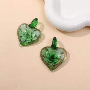 Macro shot of two green glass heart pendants with gold glitter and floral details