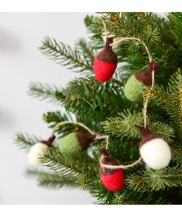 Close-up of wool felt acorn garland with red green and white colors on pine branch