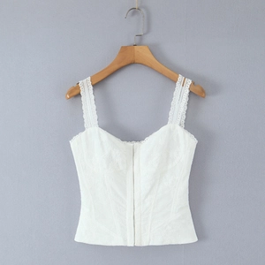 Detailed macro view of white floral lace embroidery and metal buckle on slim camisole top