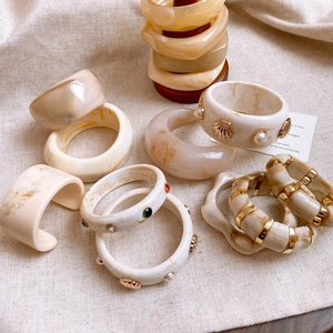 Minimalist resin bracelets in marble patterns with pearl and shell accents on linen