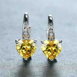 Macro view of heart-cut yellow gemstone earrings with sparkling white gold plating