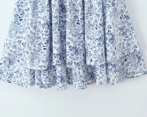 Detail view of the multi-layered skirt hem featuring a blue floral print on white fabric