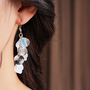 Gros plan de boucles d'oreilles à pompons pétales bleu et blanc sur un mannequin