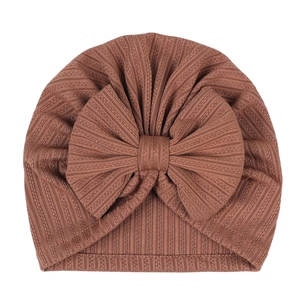 Detailed close-up of brown ribbed fabric baby hat featuring a large decorative bow