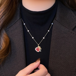 Close-up of strawberry pendant necklace with gold bow and pearls on a model