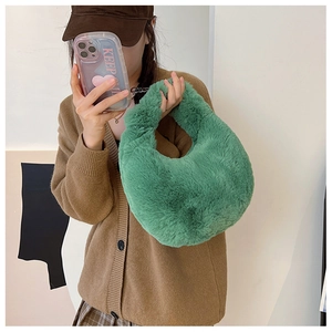 Detail of green plush faux fur shoulder bag with soft texture carried by a model