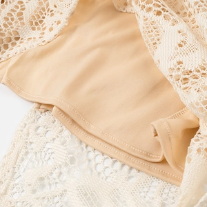 Dettaglio di abito in pizzo beige con trama traforata e cuciture di alta qualità