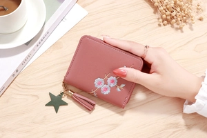 Detailed embroidery of pink flowers on a small zipper wallet with leather tassel and star charm