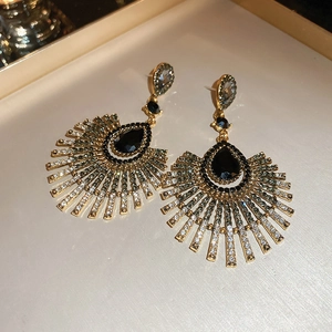 Détail de boucles d'oreilles vintage dorées avec pierre noire en goutte et strass brillants