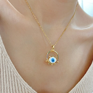 Macro shot of gold Evil Eye pendant with colorful zircon stones worn by a model