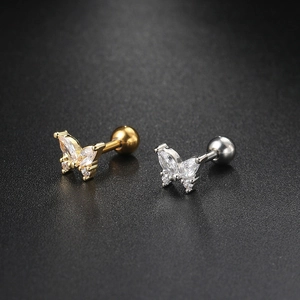 Macro shot of gold and silver butterfly cartilage studs with sparkling zircon stones