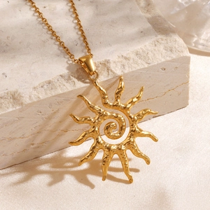 Minimalist golden sun pendant necklace with hammered texture on a silk and stone background