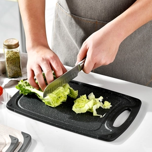 Double-sided non-slip kitchen cutting board used for chopping fresh lettuce on a countertop