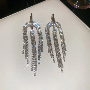 Gros plan de boucles d'oreilles demi-cercles argentées avec pampilles en strass brillants