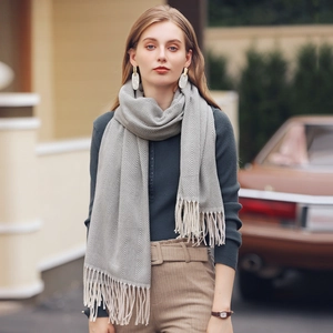 Elegant grey herringbone scarf with tassels worn by model in a stylish outdoor setting