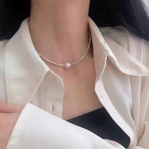Close-up of irregular silver-toned link necklace with a central white pearl on a model