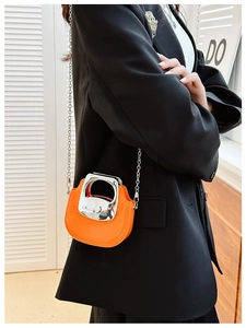 Chic orange mini crossbody bag with silver chain worn by a model in a black blazer
