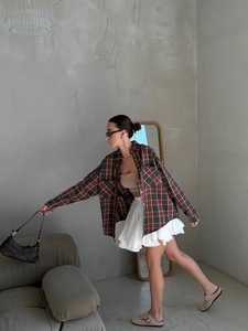 Women's vintage oversized plaid long sleeve shirt with white pleated skirt and brown bag