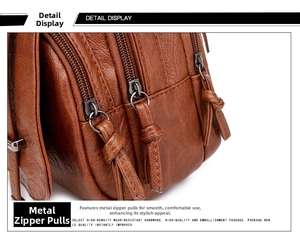 Detail of caramel brown lychee leather bag featuring multi-layer metal zippers and pullers
