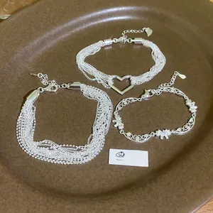 Macro detail of multilayer silver zircon heart bracelets on a brown ceramic tray